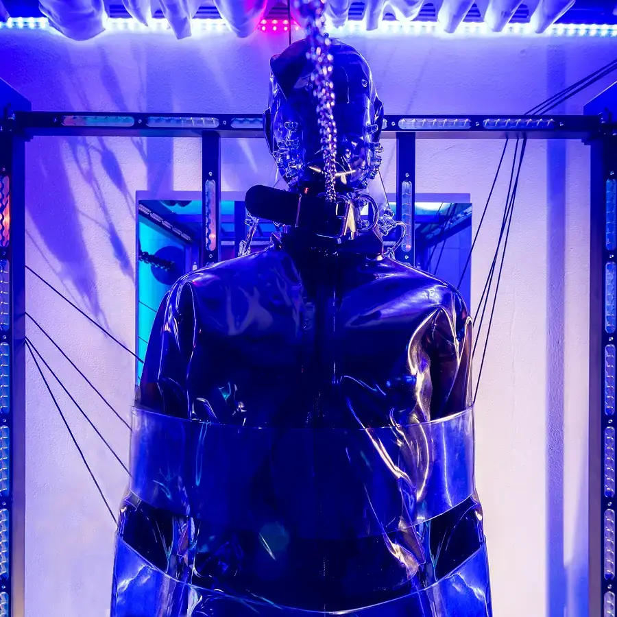 Person im Latexanzug fixiert am BDSM-Bett von Skunkworx im Dominastudio Golden Cage in Aachen NRW